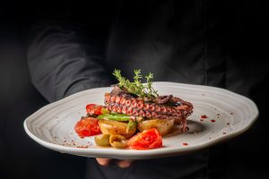 Grilled,Octopus,Served,On,Roasted,Potatoes,With,Cherry,Tomatoes,,Green