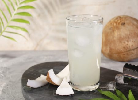 Glass,Of,Coconut,Water,,Ice,Cubes,And,Nuts,On,Grey